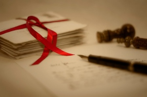 Love letters tied with red ribbon and one letter with pen.