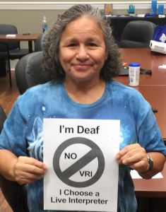 Woman holds up sign that says I'm Deaf, No VRI