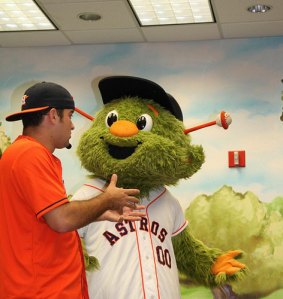 Young man in Astros fan clothes speaks with the Houston Astros furry green mascot, Orbit.