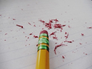 Pencil eraser over notebook paper with pieces of the eraser on the paper.